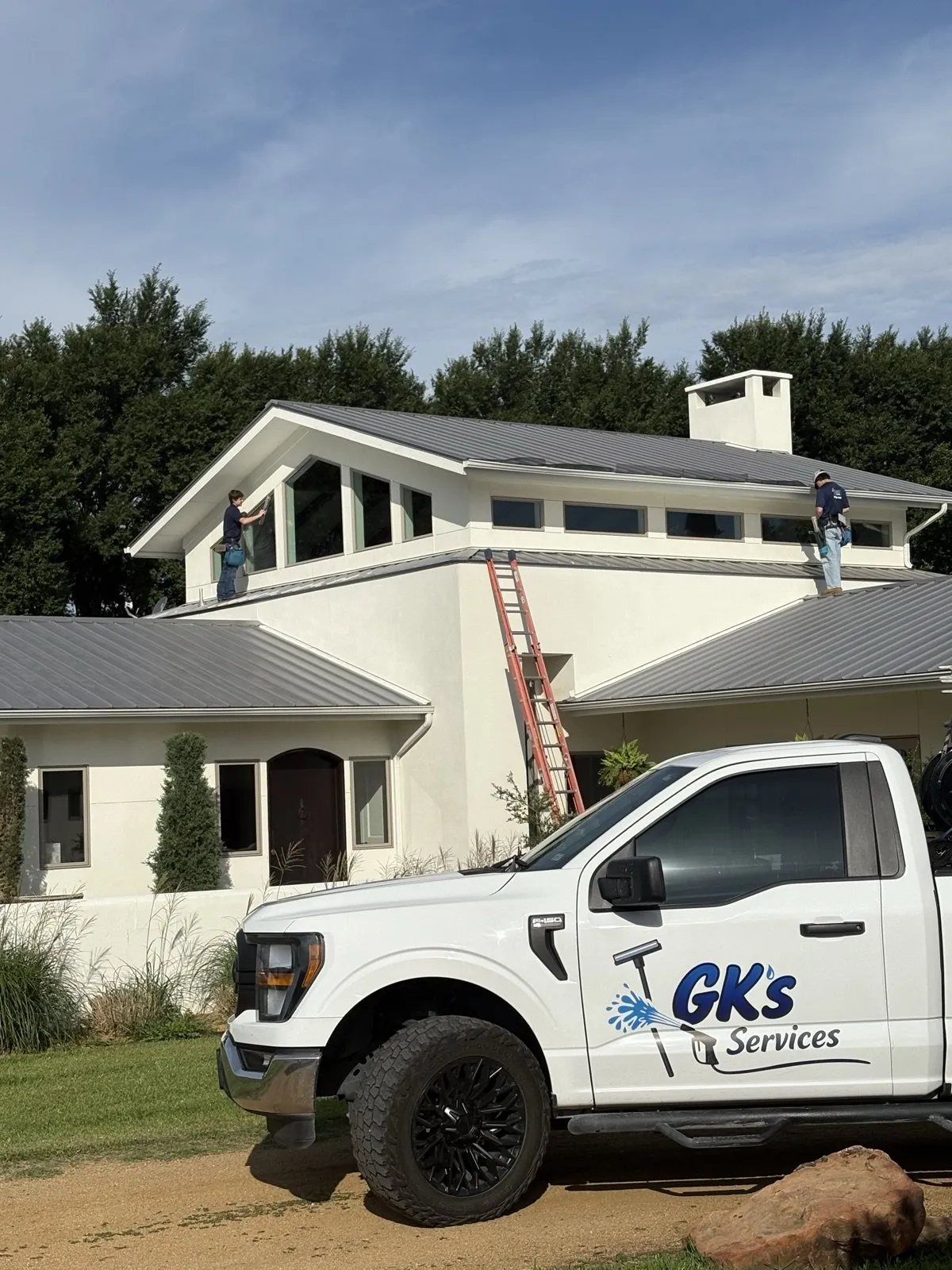 A GK's Services truck parked outside a two-story home while the crew cleans the windows