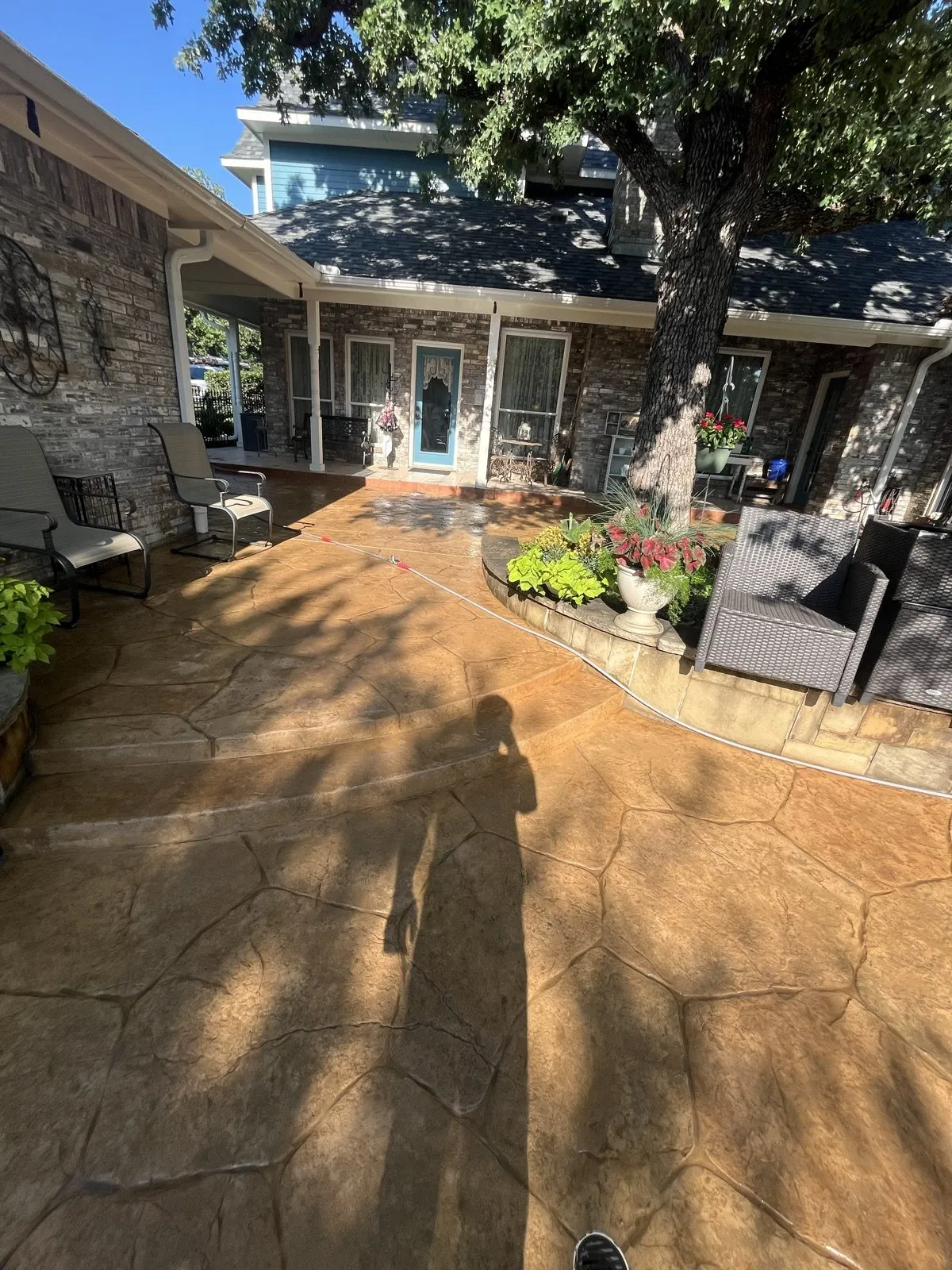 A freshly power-washed stamped-concrete patio beside a brick home