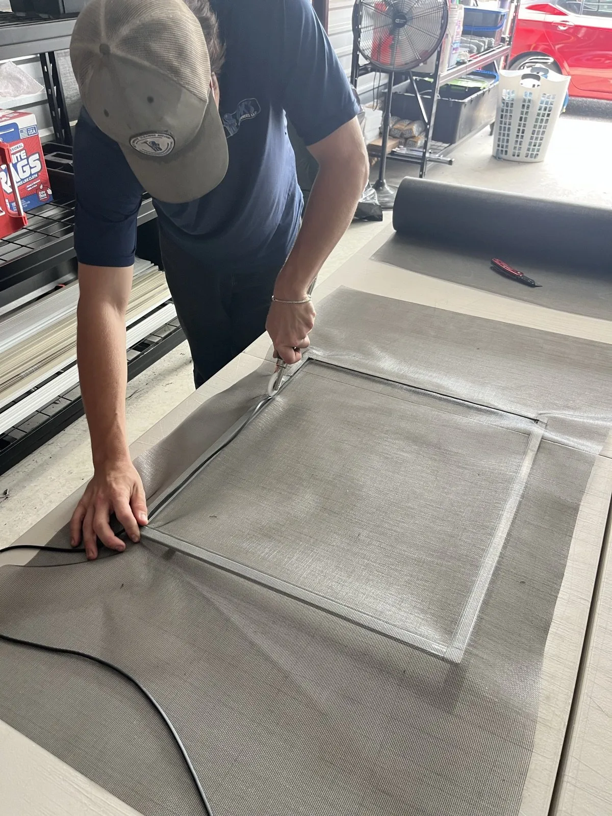 A GK's team member rebuilding a window screen in the workshop